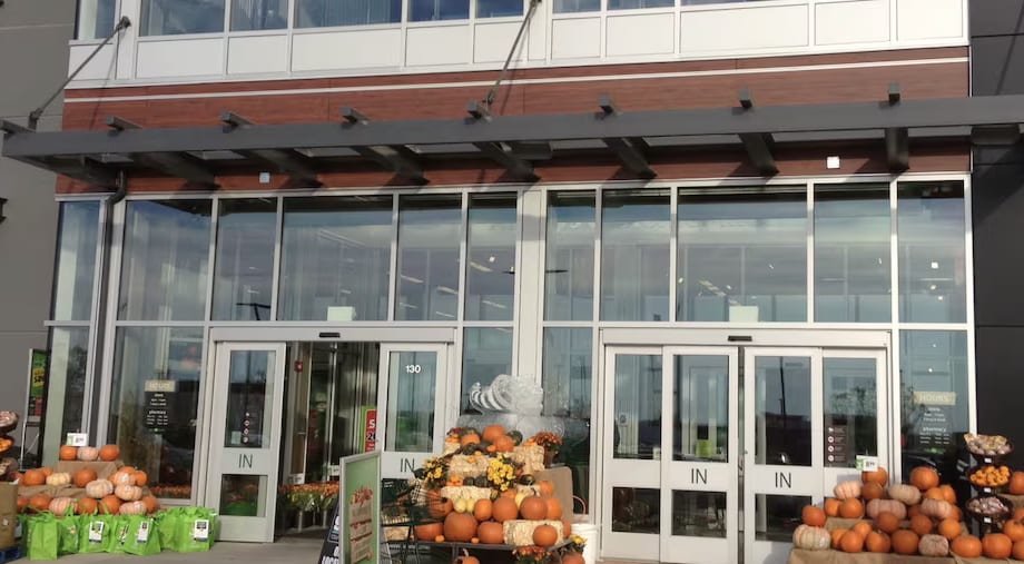 A glass storefront entrance: a two-storey curtain wall of glass over a row of four automatic sliding doors.